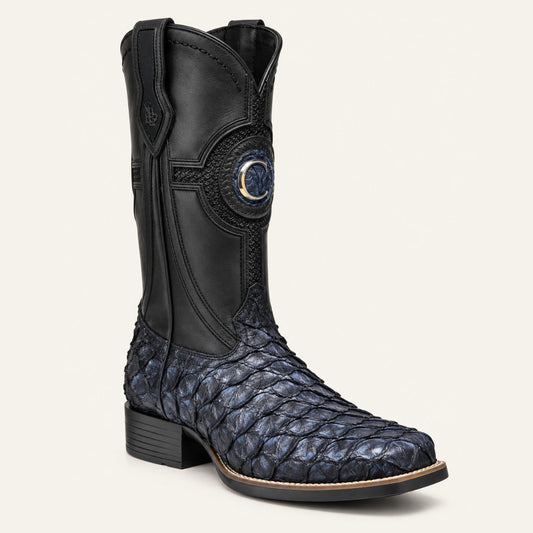 A single western boot shown in a clean studio shot against a light off-white background. The boot features a black leather shaft with decorative stitching and a circular blue-and-gold concho emblem, paired with a dark blue and black scaled snakeskin-patterned foot.